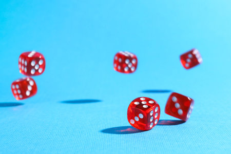 Many red game dices falling on light blue backgroundの写真素材