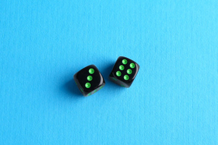 Two black game dices on light blue background, flat layの写真素材