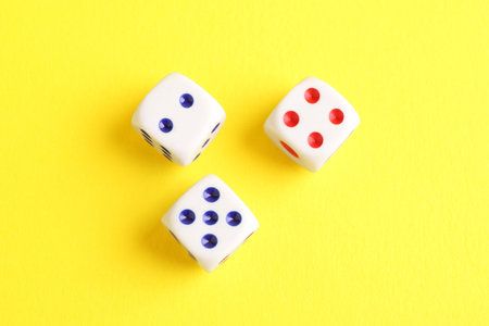 Three white game dices on yellow background, flat lay. Space for textの写真素材