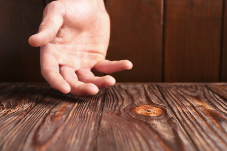 Man holding hand above wooden table, closeup. Space for textの写真素材