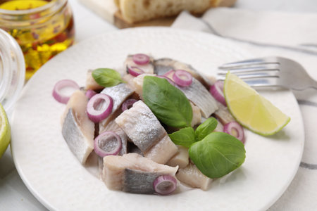 Plate with tasty marinated fish, onion and basil on light table, closeupの写真素材