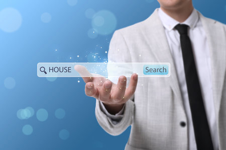 Real estate agent holding virtual search bar with word House on blue background, closeup