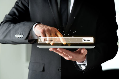 Businessman using tablet to find house, closeup. Search bar over deviceの写真素材