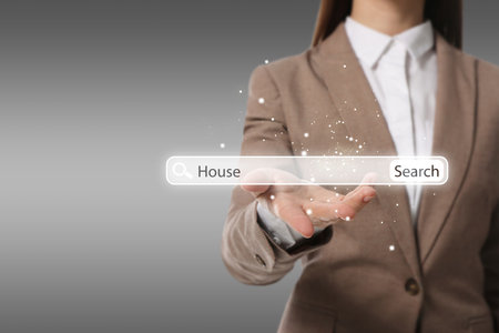Real estate agent holding virtual search bar with word House on gray background, closeup. Space for textの写真素材