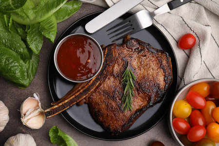 Tasty grilled meat, rosemary and marinade served on brown textured table, flat layの写真素材