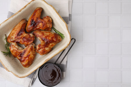 Fresh marinade, chicken wings and rosemary on white tiled table, top view. Space for textの写真素材