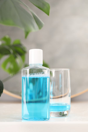 Bottle of mouthwash and glass on white table in bathroomの写真素材