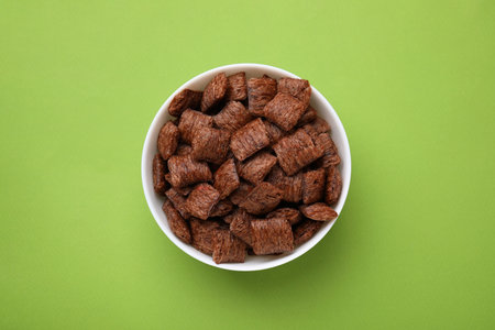 Chocolate cereal pads in bowl on green table, top viewの写真素材