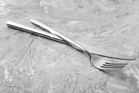 Stylish cutlery. Silver knife and fork on gray textured table