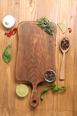 Cutting board, spices and lime on wooden table, flat lay. Space for textの写真素材