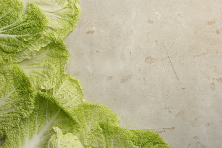 Fresh Chinese cabbage leaves on gray textured table, top view. Space for textの写真素材