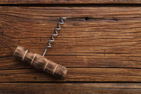 One corkscrew on wooden table, top view. Space for text