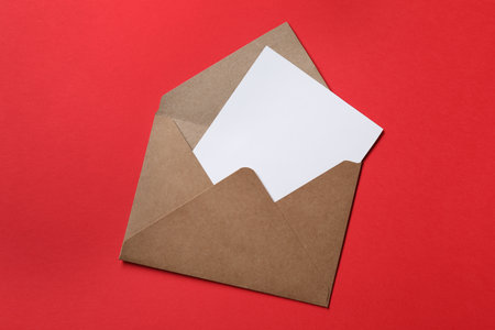 Letter envelope with card on red background, top view