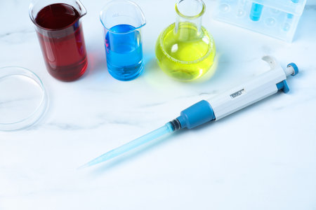 Laboratory analysis. Micropipette, petri dish and other glassware on white marble tableの写真素材
