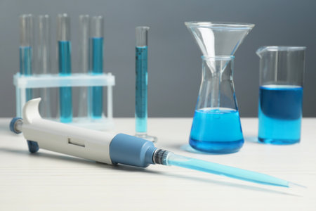 Laboratory analysis. Micropipette and different glassware with liquids on white wooden table, closeupの写真素材