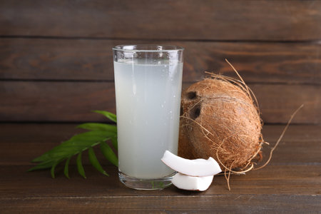 Glass of coconut water, leaf and nuts on wooden tableの写真素材