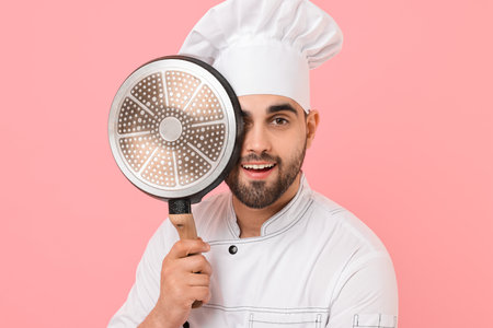 Professional chef with frying pan on pink backgroundの写真素材