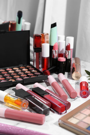 Bright lip glosses among different cosmetic products on white dressing tableの写真素材