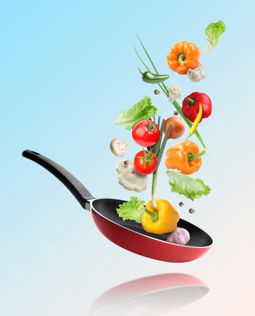 Frying pan and different vegetables in air on light blue gradient backgroundの写真素材