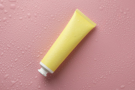 Moisturizing cream in tube on pink background with water drops, top viewの写真素材