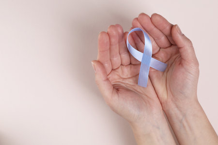 International Psoriasis Day. Woman with light blue ribbon as symbol of support on beige background, top view. Space for textの写真素材