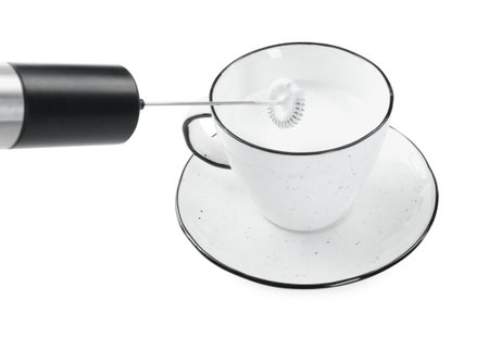Whisking milk in cup with mini mixer (frother wand) isolated on whiteの写真素材