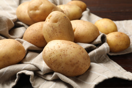 Raw fresh potatoes and napkin on wooden table, closeupの写真素材