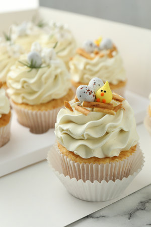 Tasty Easter cupcakes with vanilla cream on white marble table, closeupの写真素材