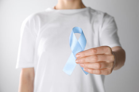 International Psoriasis Day. Woman with light blue ribbon as symbol of support on white background, closeupの写真素材
