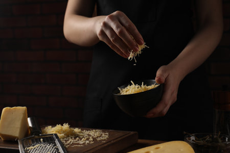 Woman with gratified cheese at wooden table, closeupの写真素材