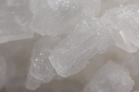 White natural salt as background, closeup view