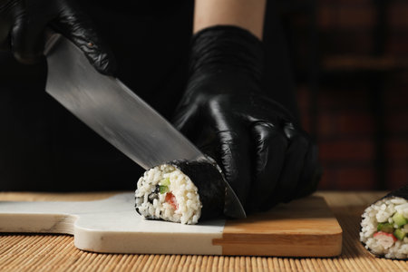 Chef in gloves cutting sushi roll at table, closeupの写真素材