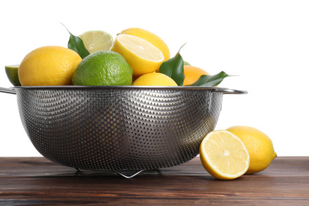 Metal colander with citrus fruits on wooden table against white backgroundの写真素材