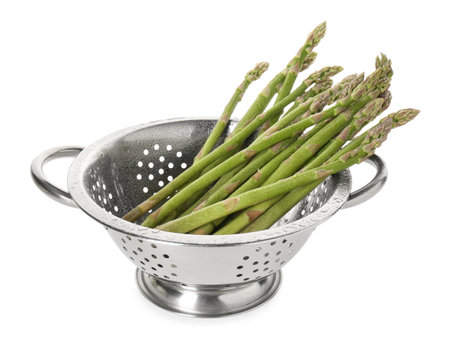 Metal colander with asparagus isolated on whiteの写真素材