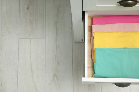 Chest of drawers with different folded clothes indoors, top view. Space for textの写真素材