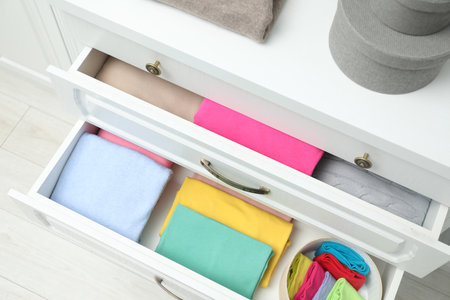 Chest of drawers with different folded clothes indoors, top viewの写真素材