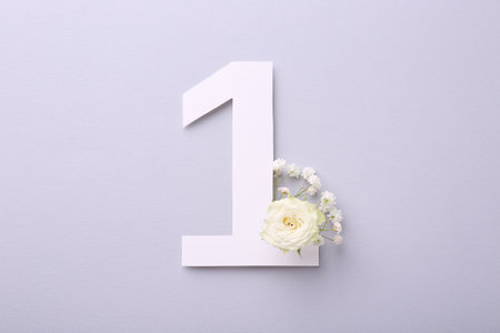 Paper number 1 and beautiful flowers on light gray background, top view