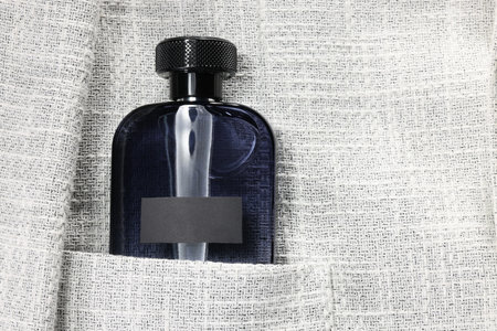 Luxury men's perfume in pocket of gray jacket, top view. Space for textの写真素材