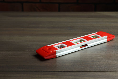 Red building level on wooden table. Construction tool
