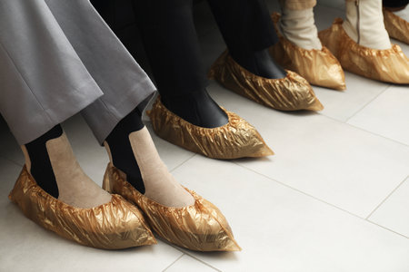 Women wearing shoe covers onto different footwear indoors, closeupの写真素材