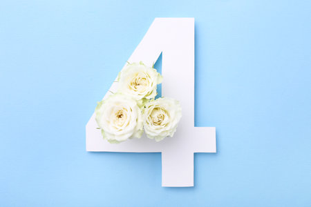 Paper number 4 and beautiful flowers on light blue background, top view