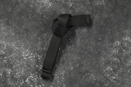 Black karate belt on gray textured background, top viewの写真素材