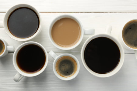 Different coffee drinks in cups on white wooden table, flat layの写真素材