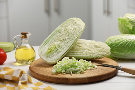 Fresh Chinese cabbages, knife and oil on white wooden table in kitchenの写真素材