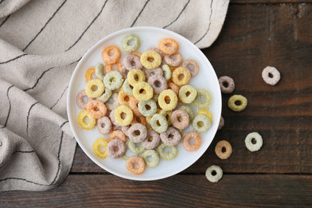 Cereal rings and milk in bowl on wooden table, top view