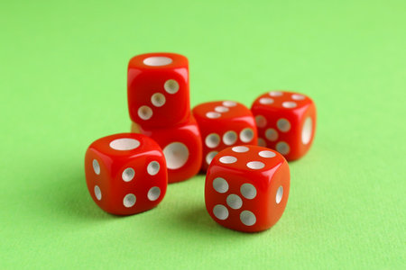 Many red game dices on green background, closeup