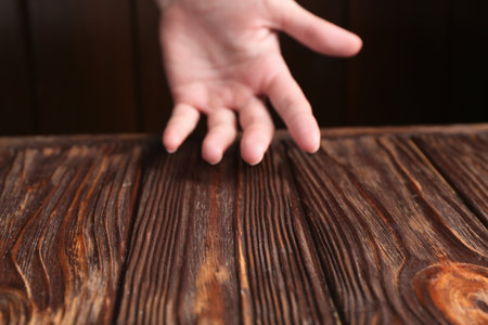 Woman holding hand above wooden table, selective focus. Space for textの写真素材