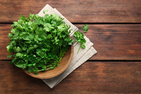 Fresh coriander in bowl on wooden table, top view. Space for textの写真素材