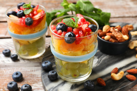 Delicious fruit salad, fresh berries, mint and nuts on wooden tableの写真素材