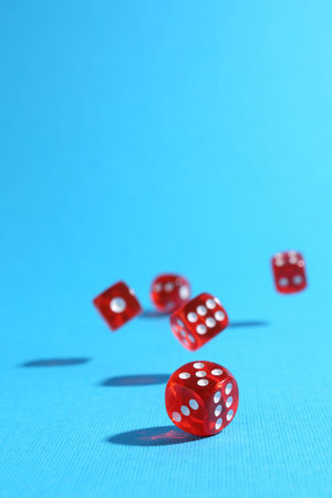 Many red game dices falling on light blue background. Space for text